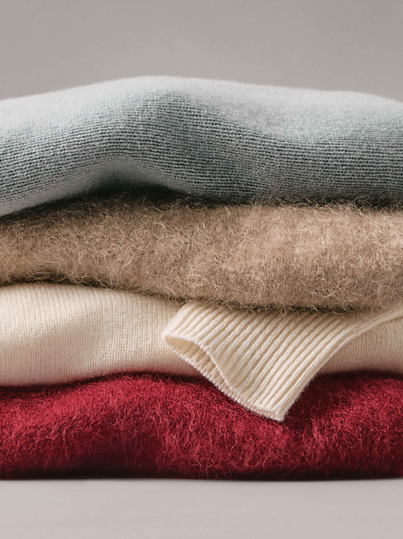 Cozy Cashmere — a stack of soft cashmere sweaters in sage, oatmeal, ivory and red. Shop Now.