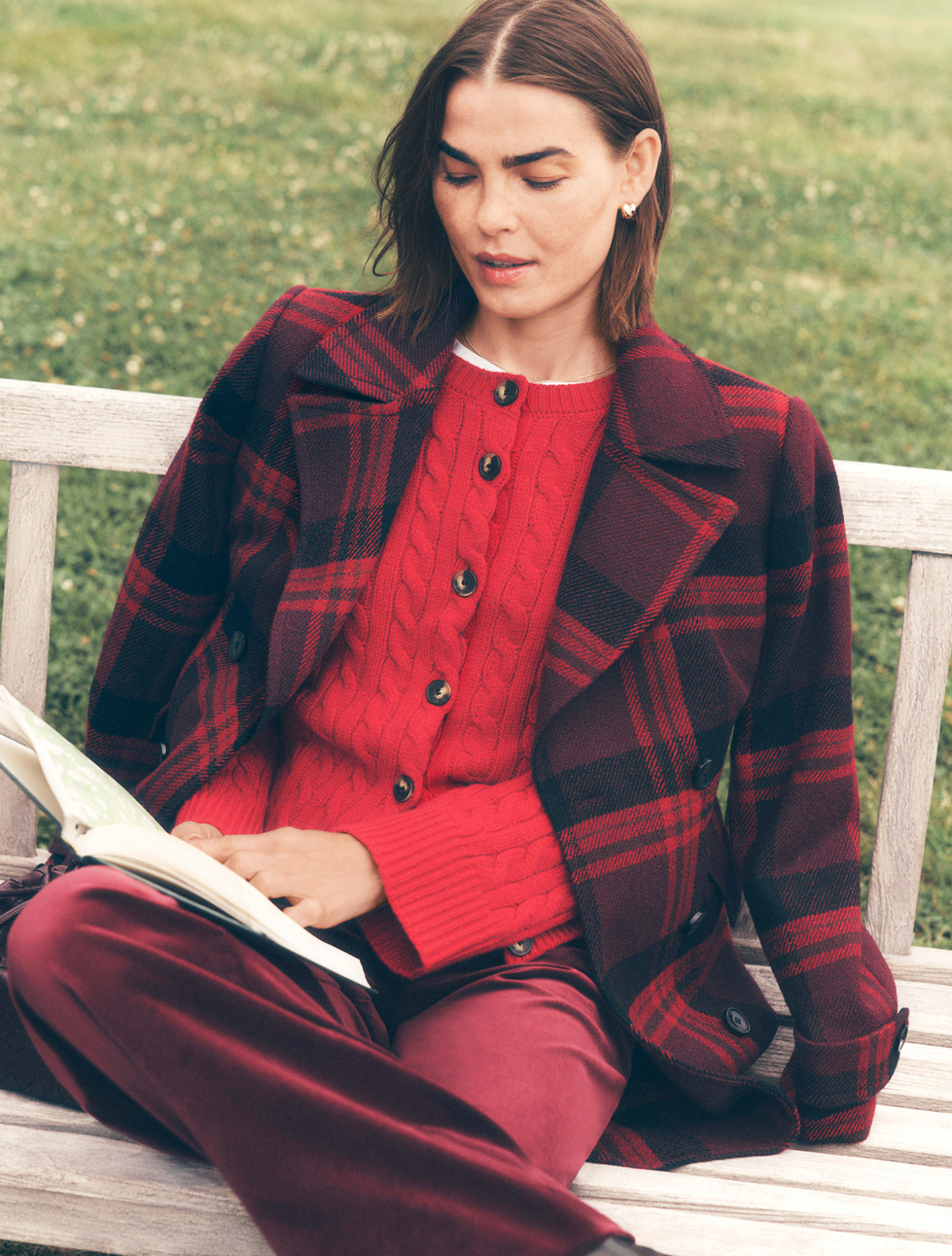 The Weekend Collection — a model reading in a plaid coat and red cardigan. Shop Effortless Outfitting.