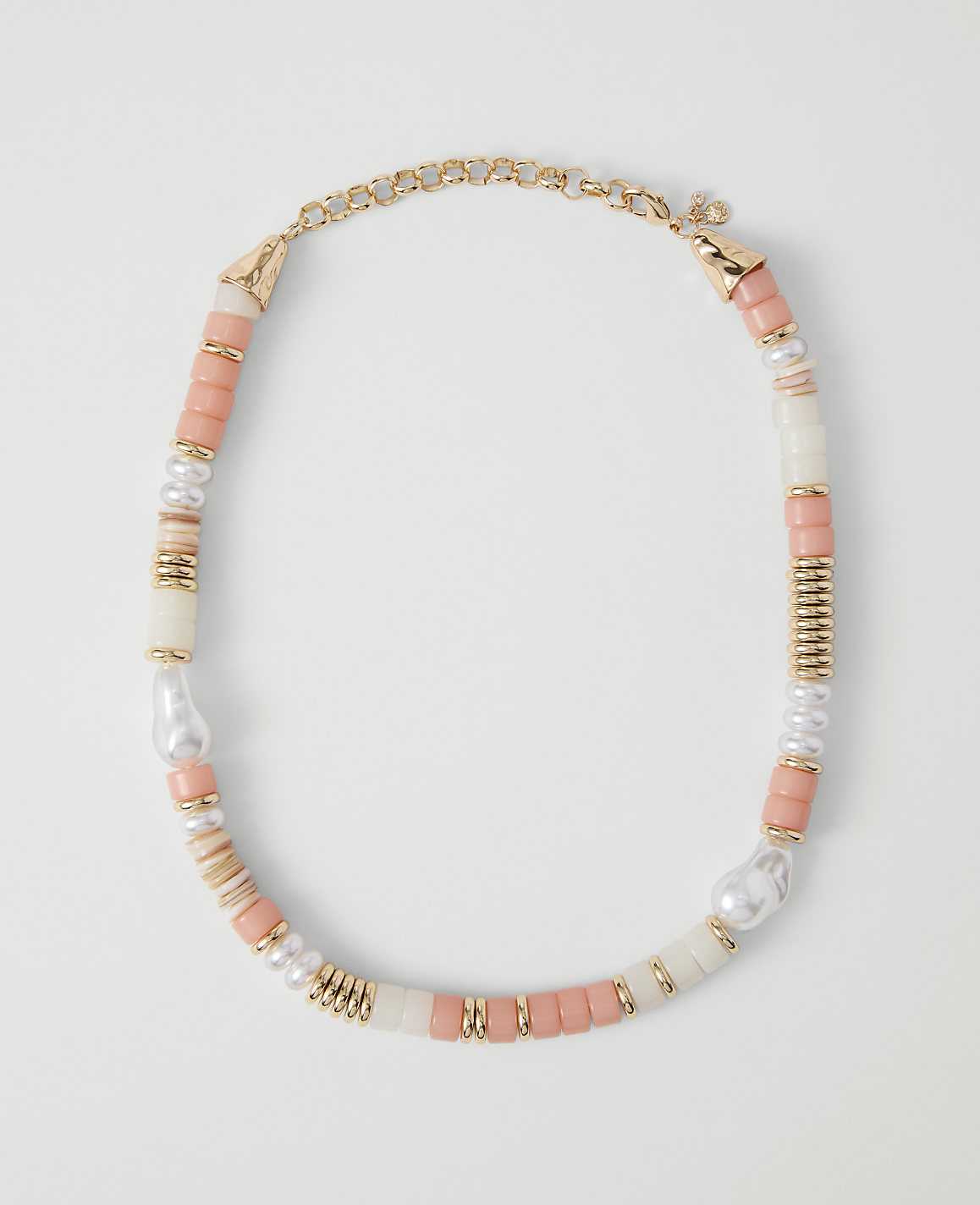 A coral, pearl, and gold beaded necklace rests on a plain white background.
