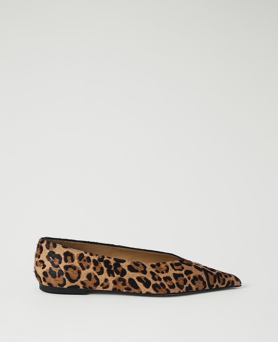 A pointed-toe leopard print flat shoe rests on a plain white background.