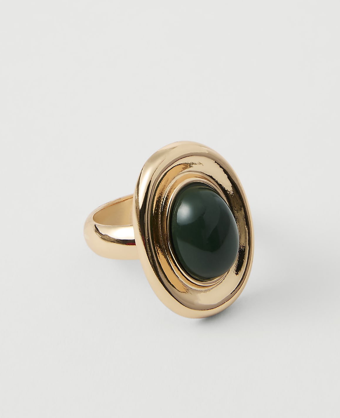 A gold ring with a dark green oval stone sits on a plain white background.
