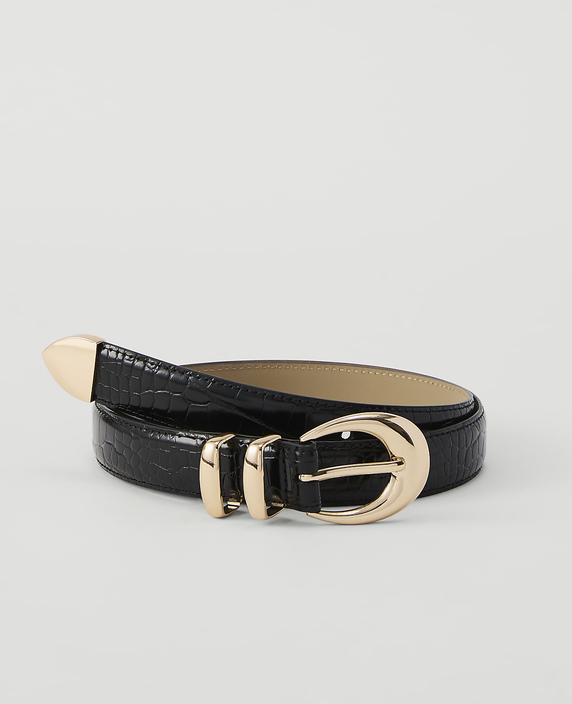 A black, crocodile-textured belt with gold hardware lies on a plain white background.