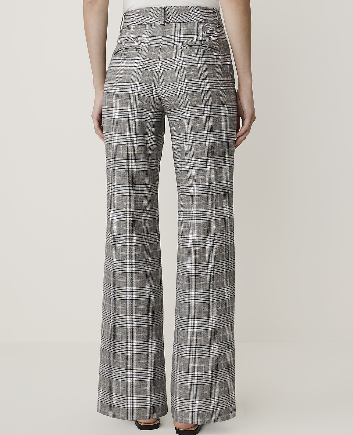 A person wearing high-waisted, wide-leg plaid pants stands against a plain white background.