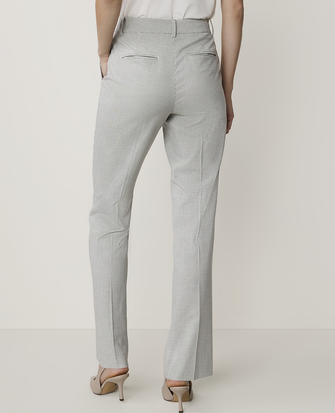 A person wearing checkered pants and heels stands against a plain white background.