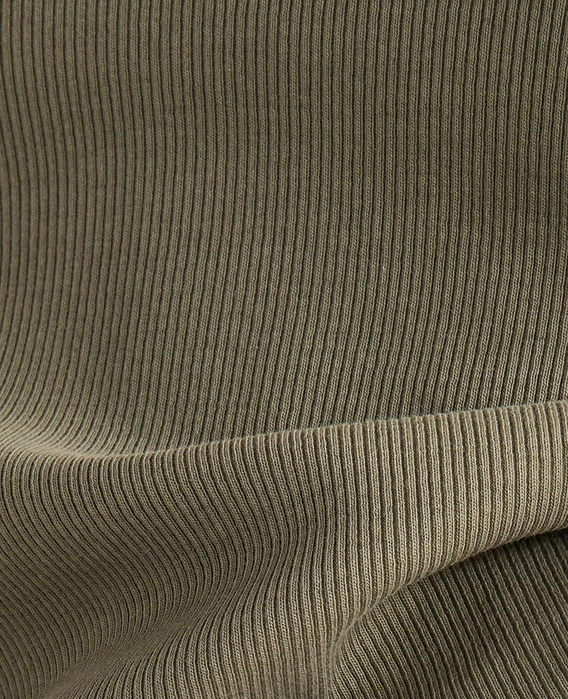 A close-up view of olive green ribbed fabric shows a folded hem in the foreground against a backdrop of vertical ribbing.