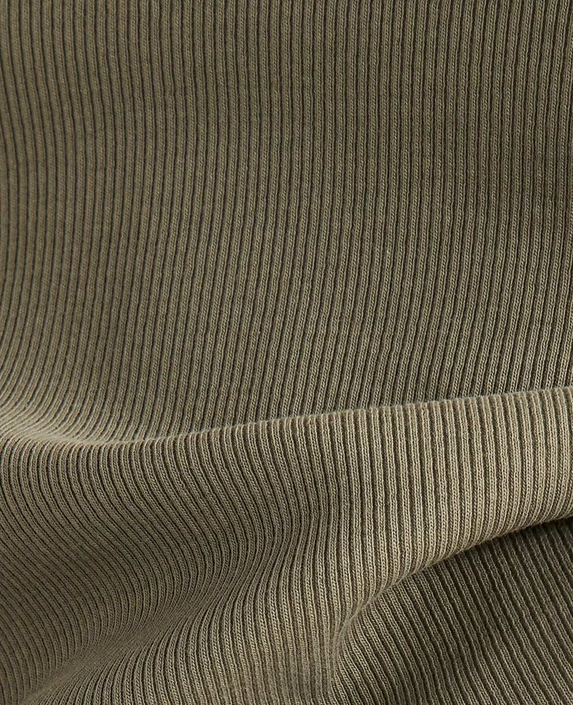 A close-up view of olive green ribbed fabric in the foreground folds over a similar textured background.