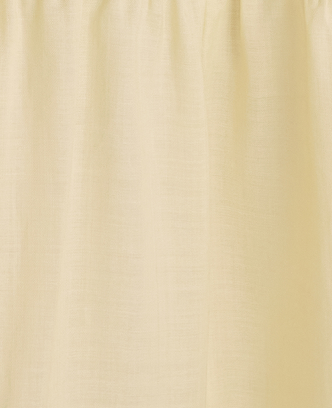A pale yellow curtain with soft folds hangs in front of a subtly textured, lighter background.