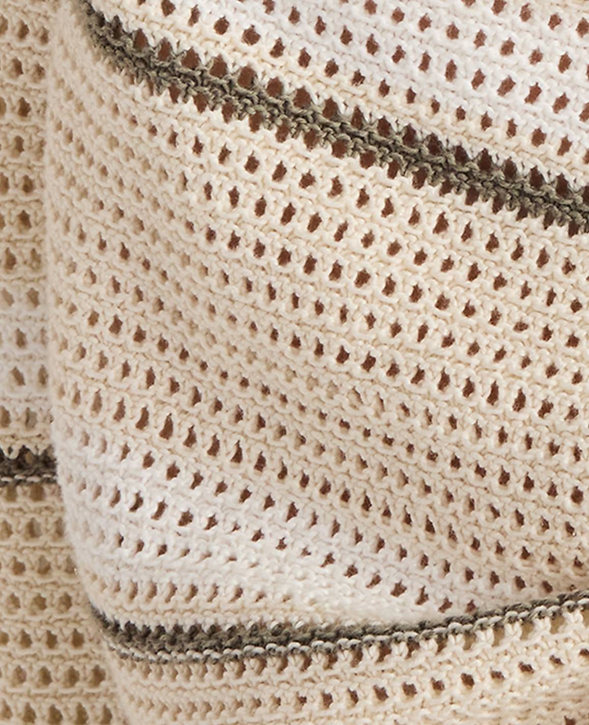 A close-up of a cream-colored crocheted fabric with thin, dark stripes is visible against a blurred, light background.