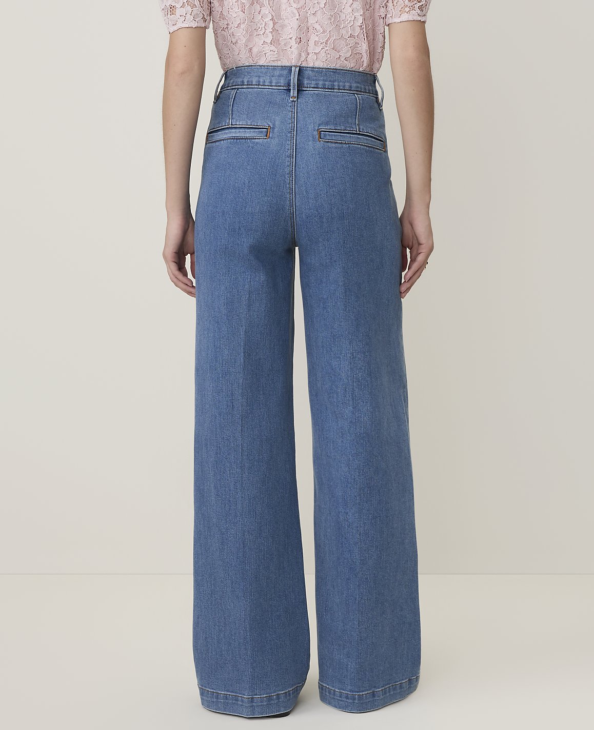 A person wearing wide-leg denim jeans stands against a plain, light-colored background.