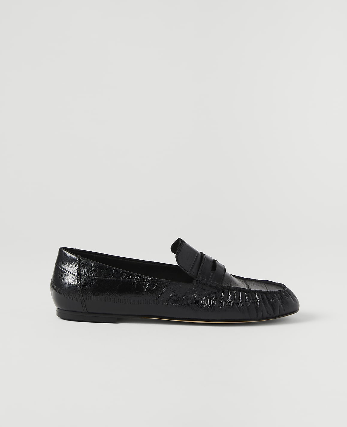 A black leather loafer rests on a plain white background.