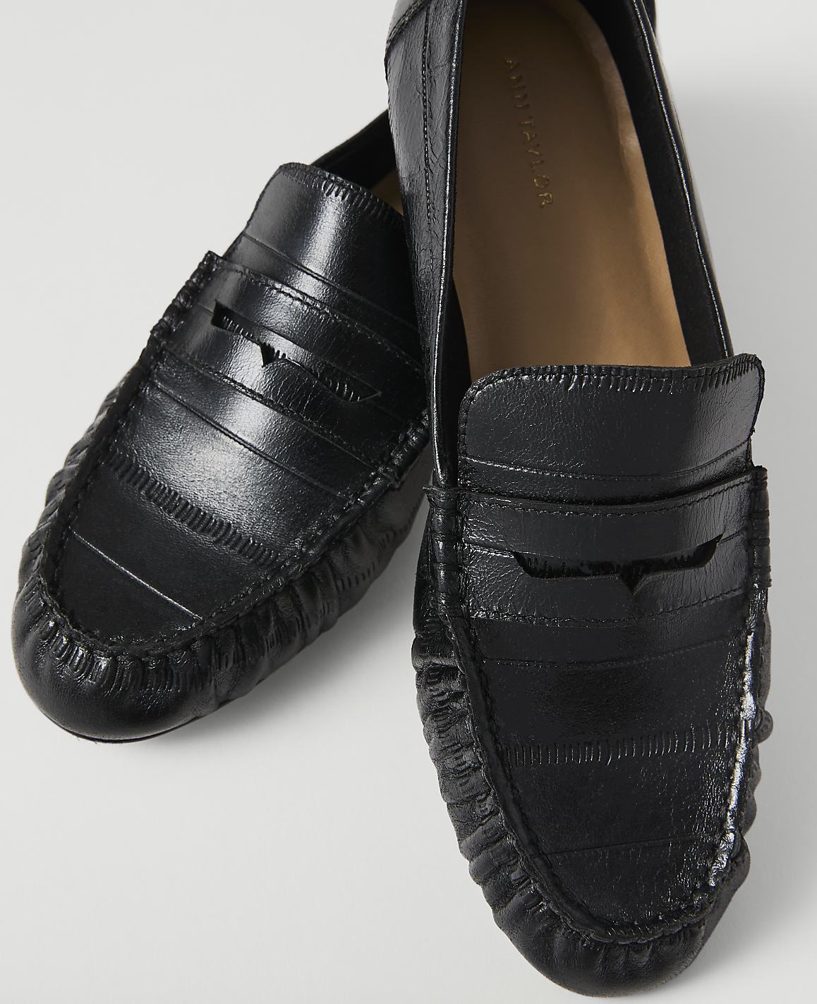 A pair of black leather loafers with a textured finish are displayed against a plain white background.