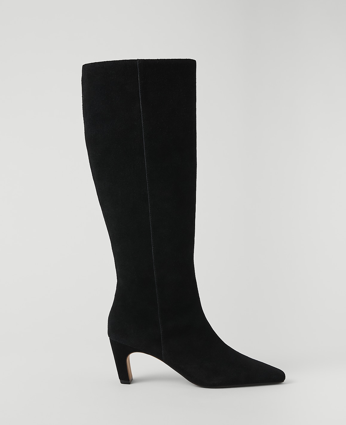 A black suede knee-high boot with a pointed toe and a low heel stands against a plain white background.