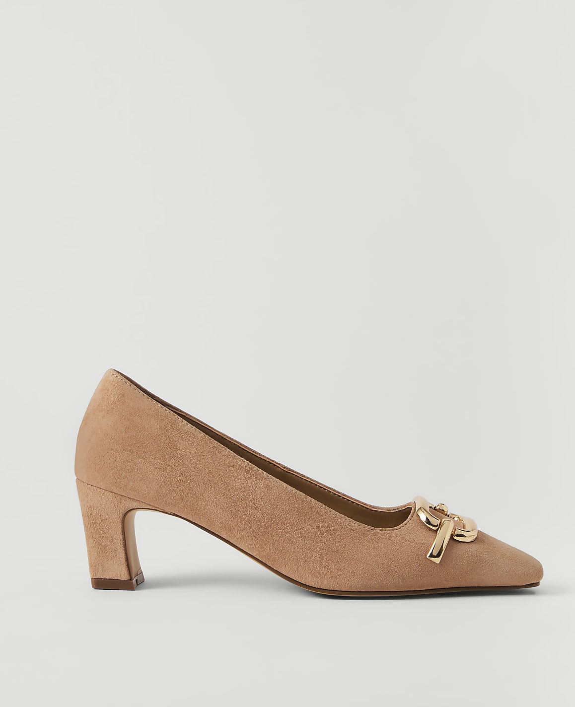 A tan suede pump with a gold buckle detail rests on a plain white background.