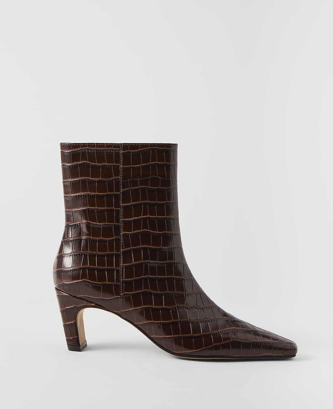 A glossy brown crocodile-embossed ankle boot with a pointed toe and a flared heel stands against a plain white background.