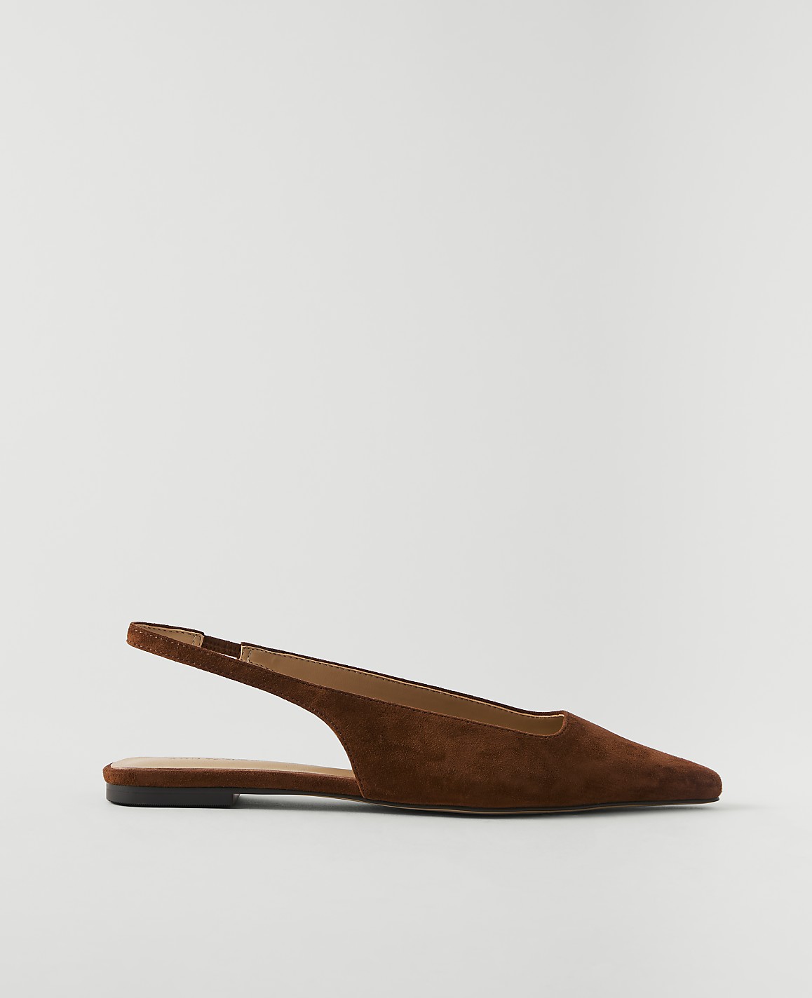 A brown suede slingback flat shoe rests on a plain white background.
