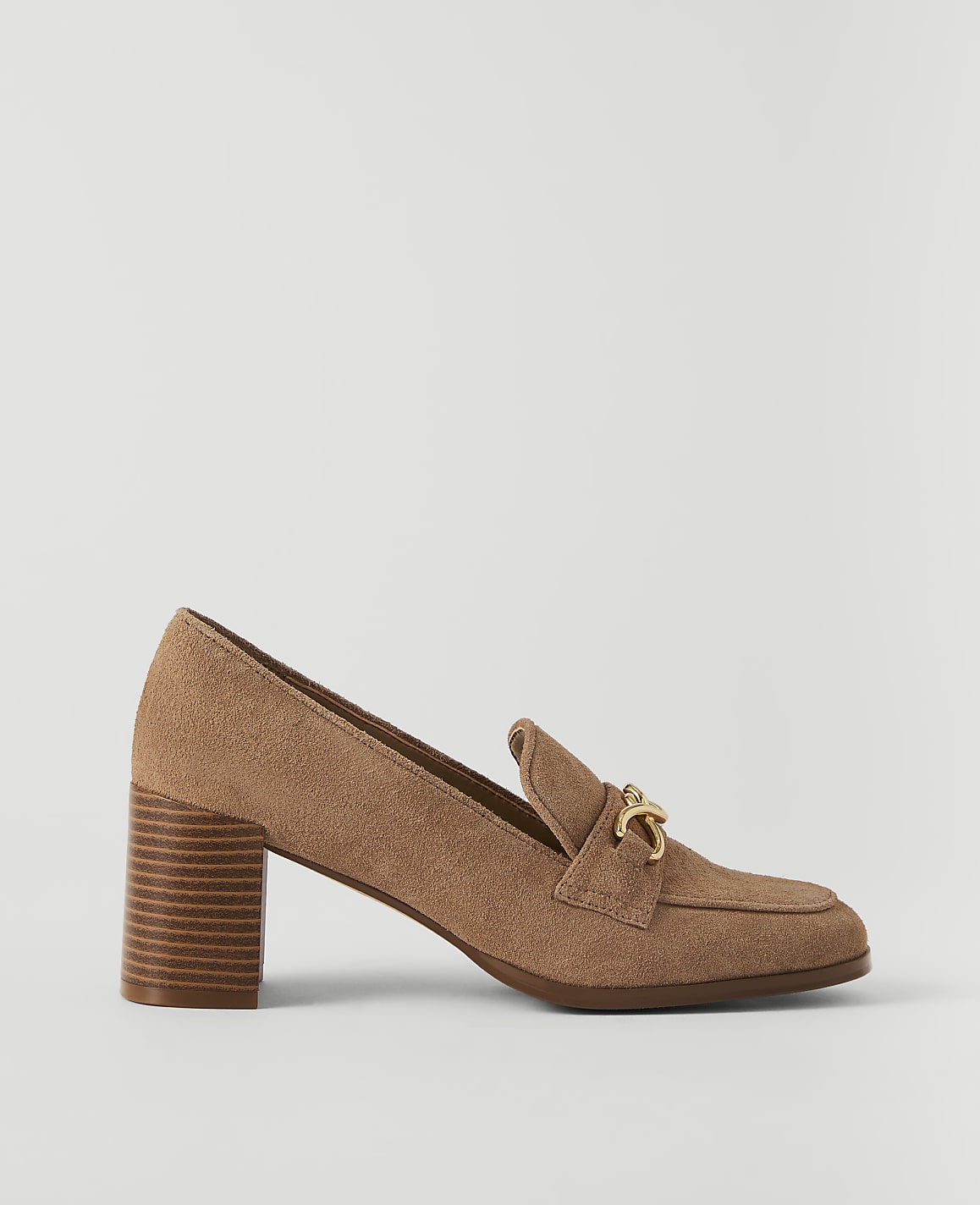 A tan suede loafer with a gold buckle sits on a plain white background.