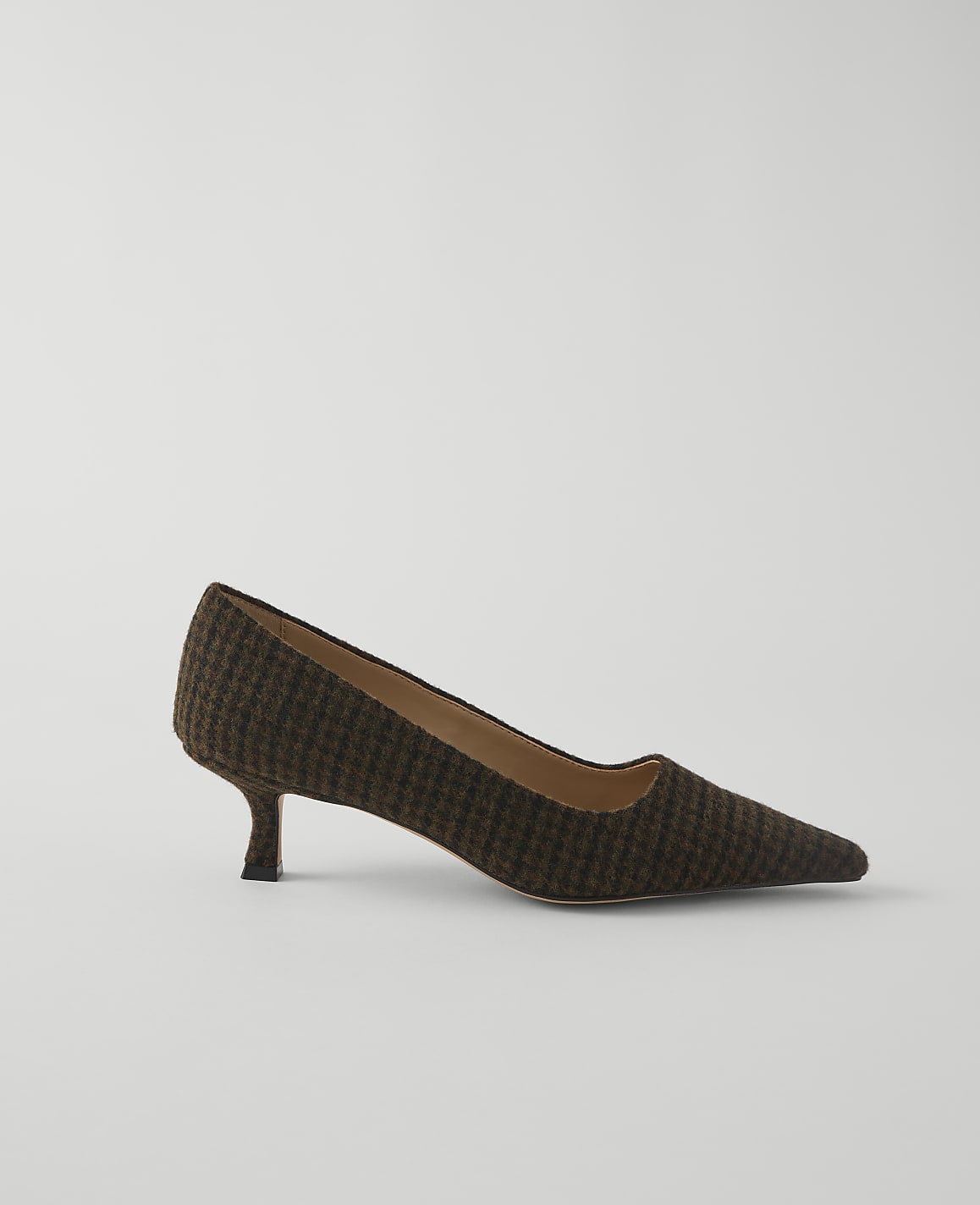 A brown and black patterned pump with a pointed toe and kitten heel rests on a plain white background.
