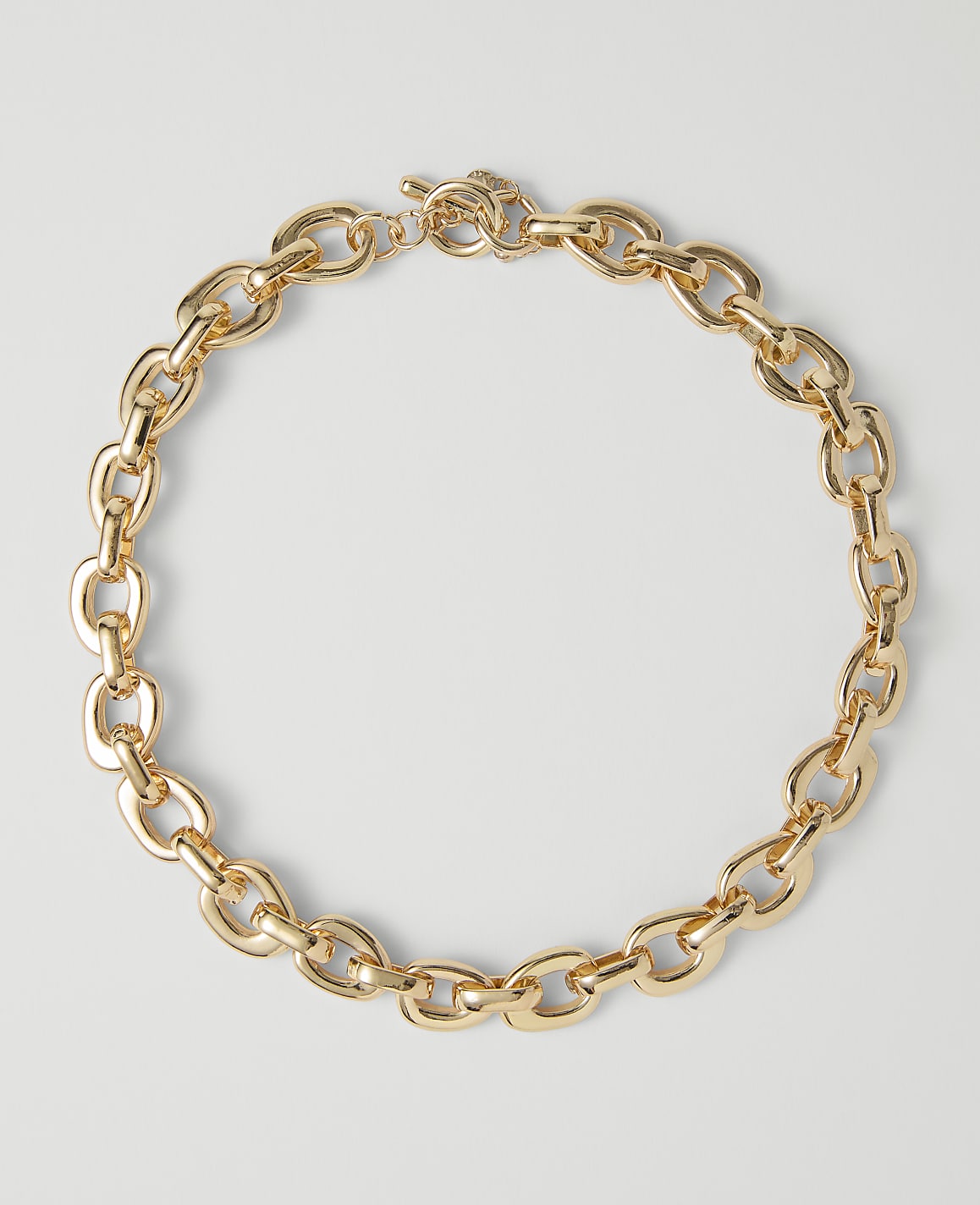 A chunky gold chain necklace with a toggle clasp rests on a plain white background.