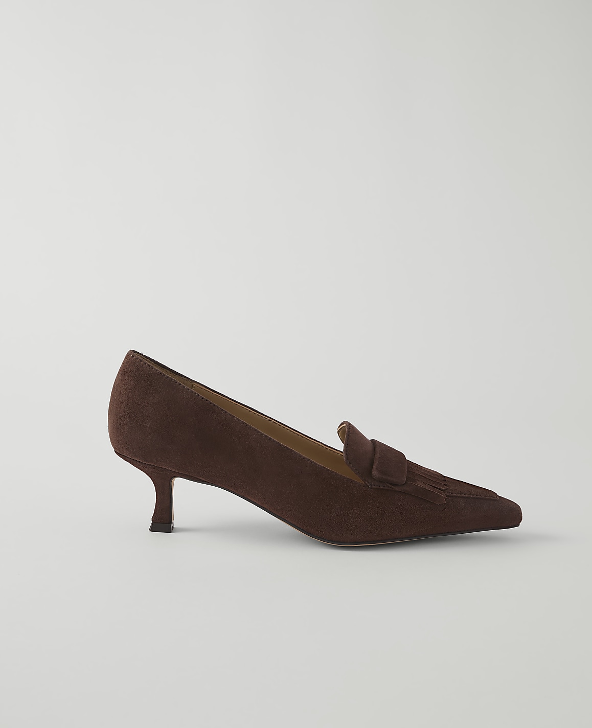 A brown suede loafer with a kitten heel rests on a plain white background.