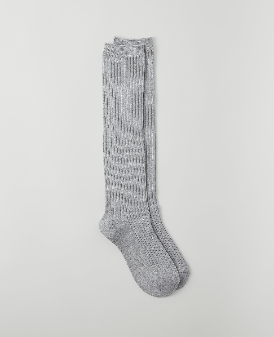 A pair of ribbed grey knee-high socks lies on a plain light grey background.