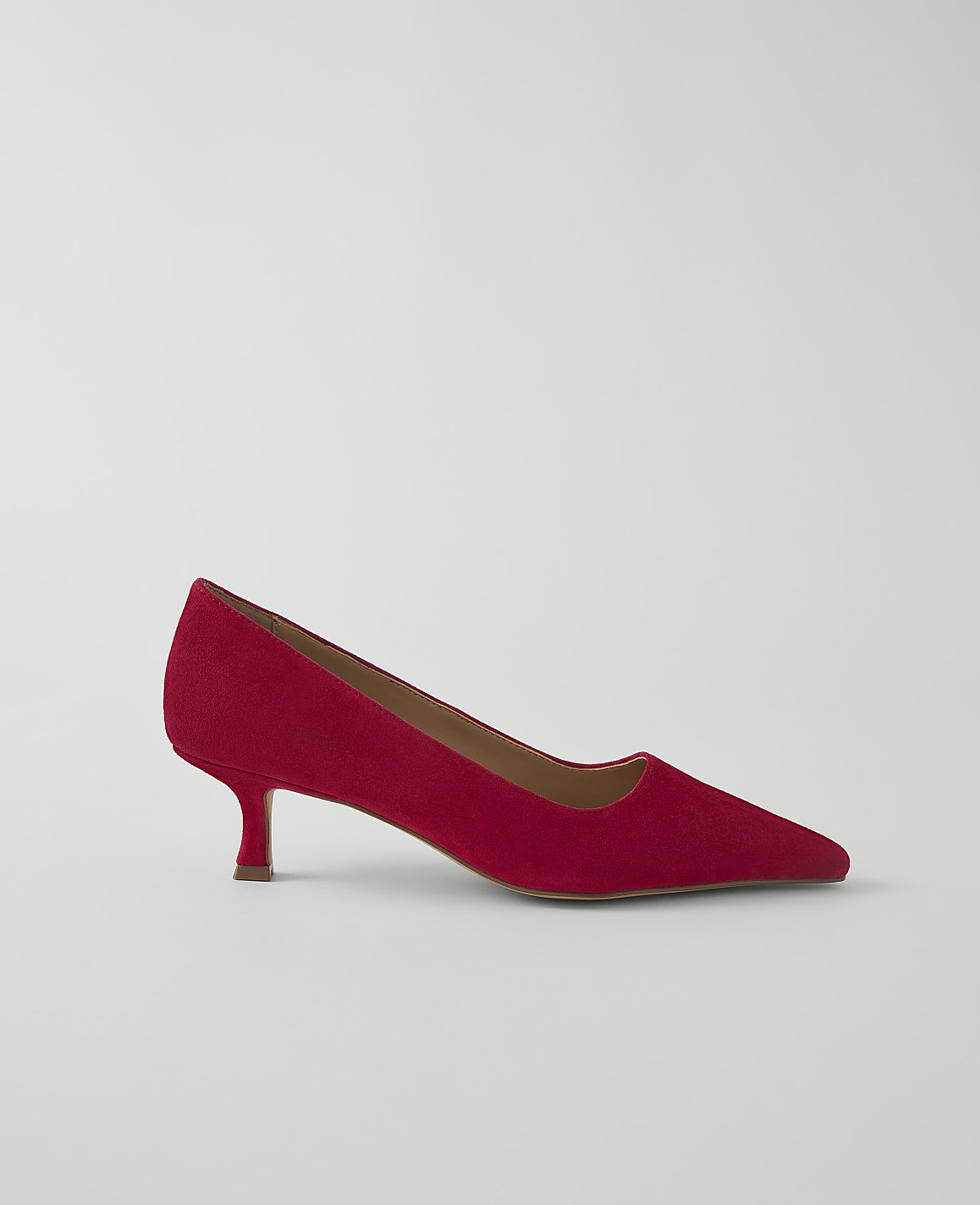 A red suede kitten heel pump rests on a plain white background.