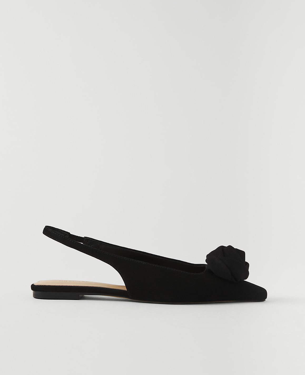 A black slingback flat with a rose embellishment sits against a plain white background.