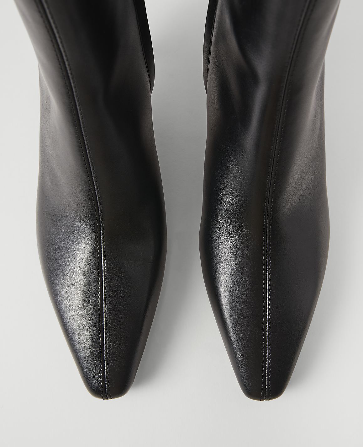 A pair of sleek black leather boots with pointed toes are presented against a plain white background.