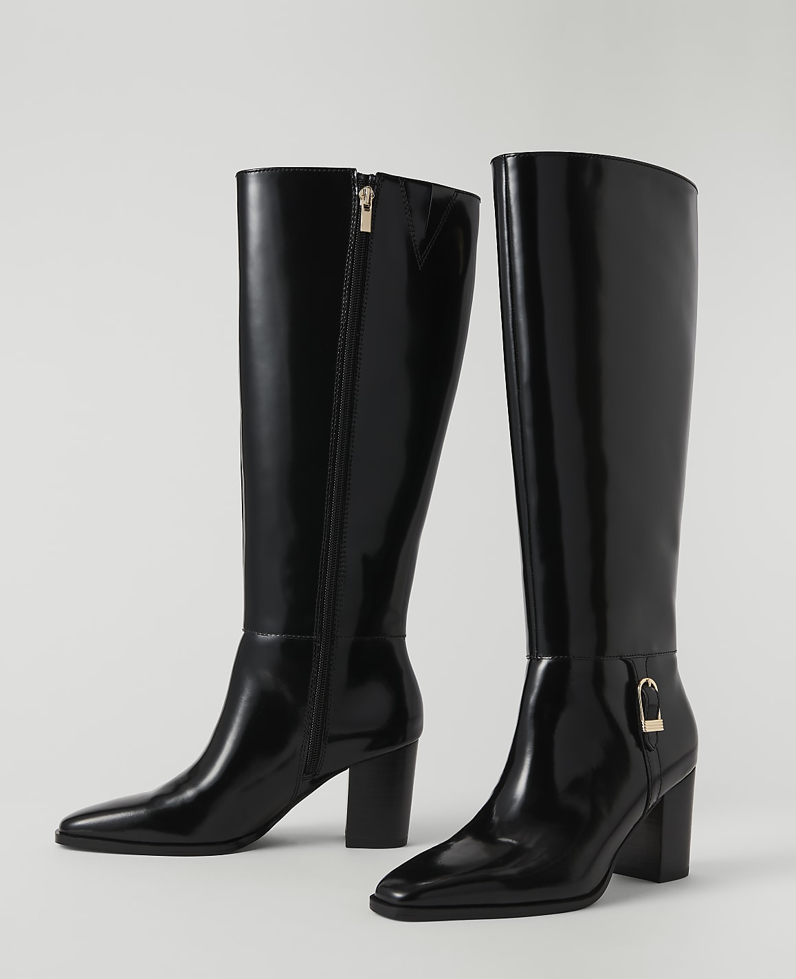 A pair of shiny black knee-high boots with gold accents stand on a plain white background.