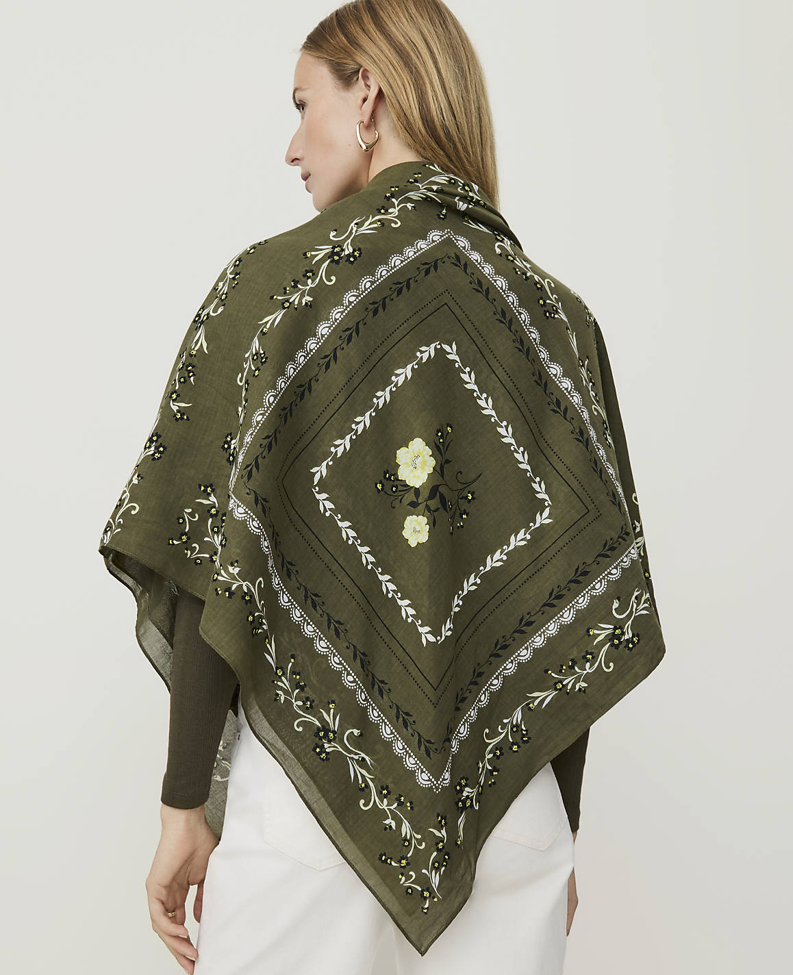 A close-up of a green fabric with a floral pattern in the foreground and a decorative border in the background.