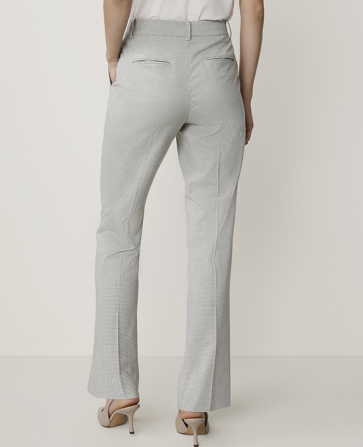 A person wearing checkered pants and heels stands against a plain white background.
