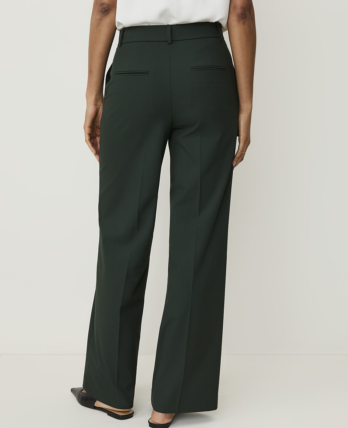 A person wearing dark green wide-leg trousers stands against a plain white background.
