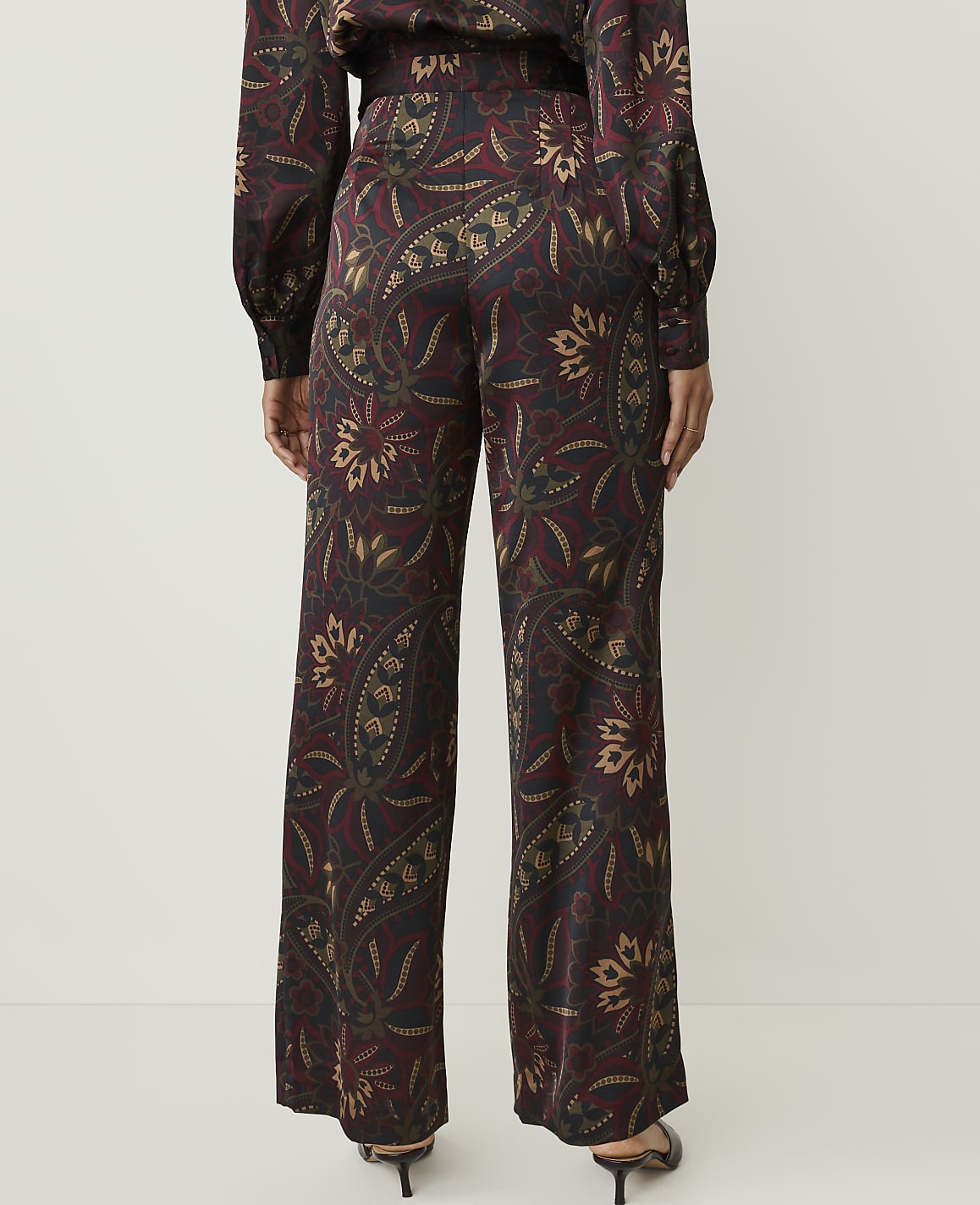 A person stands in wide-leg patterned pants against a plain white background.
