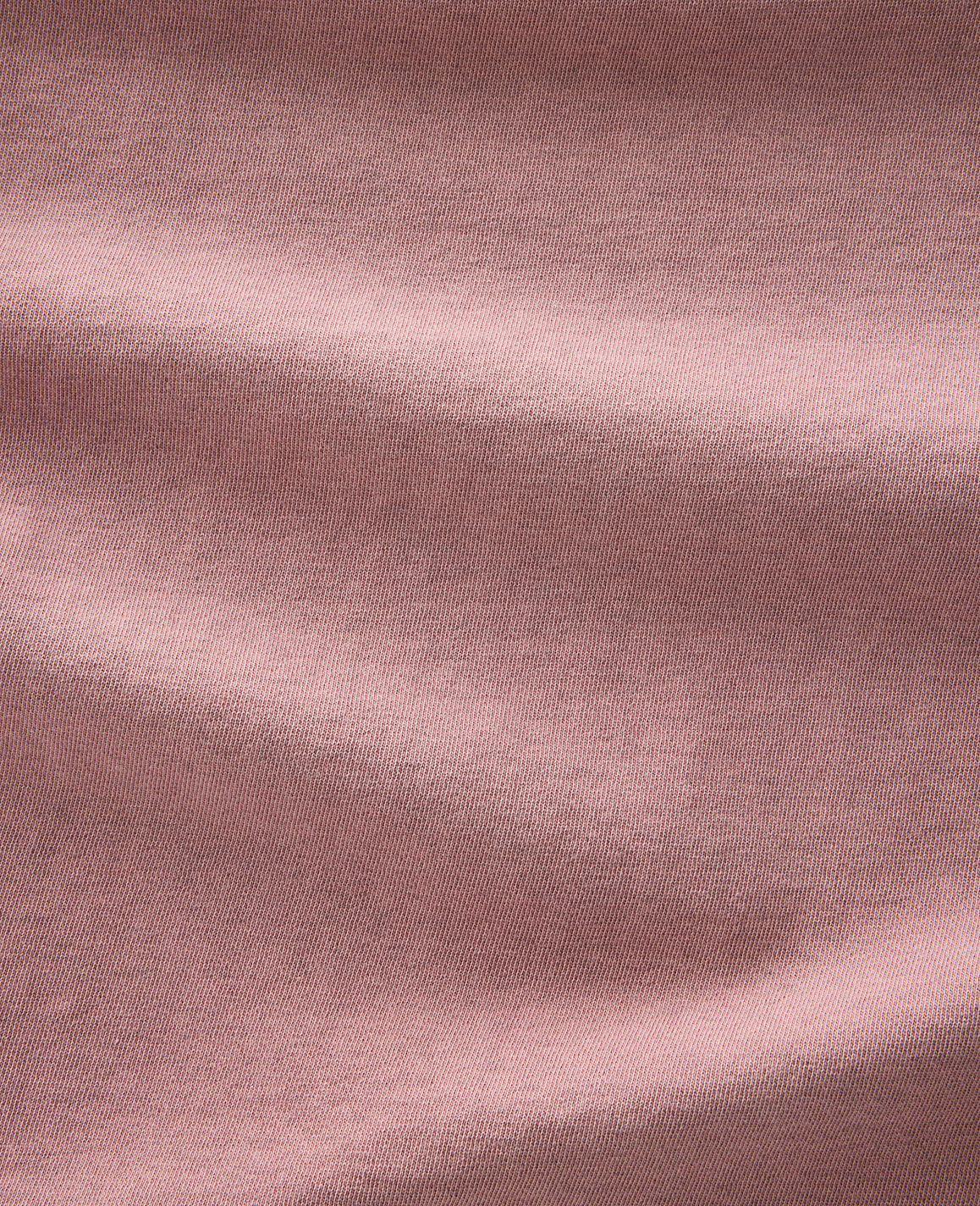 Soft, dusty rose fabric folds and creases across the frame, with subtle texture visible throughout.