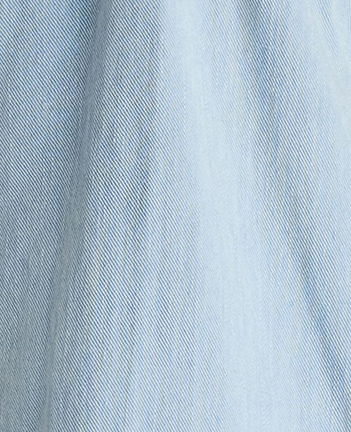 A close-up of light blue denim fabric fills the frame, with subtle vertical lines and a soft, textured weave visible throughout.