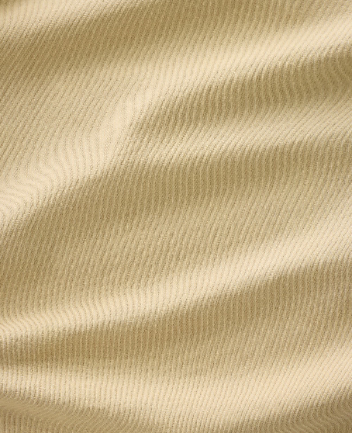 Soft, rippling folds of a light tan fabric fill the frame, creating a textured and abstract background.