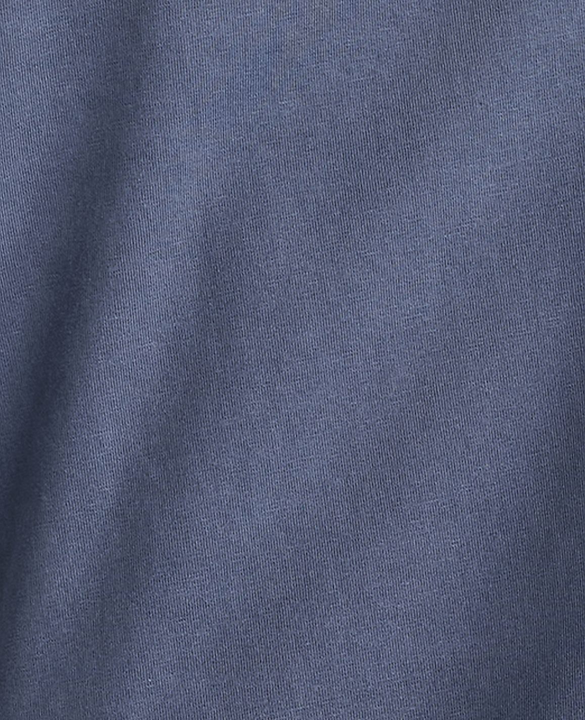 A close-up of a textured blue fabric fills the frame, with subtle folds and shadows creating depth.