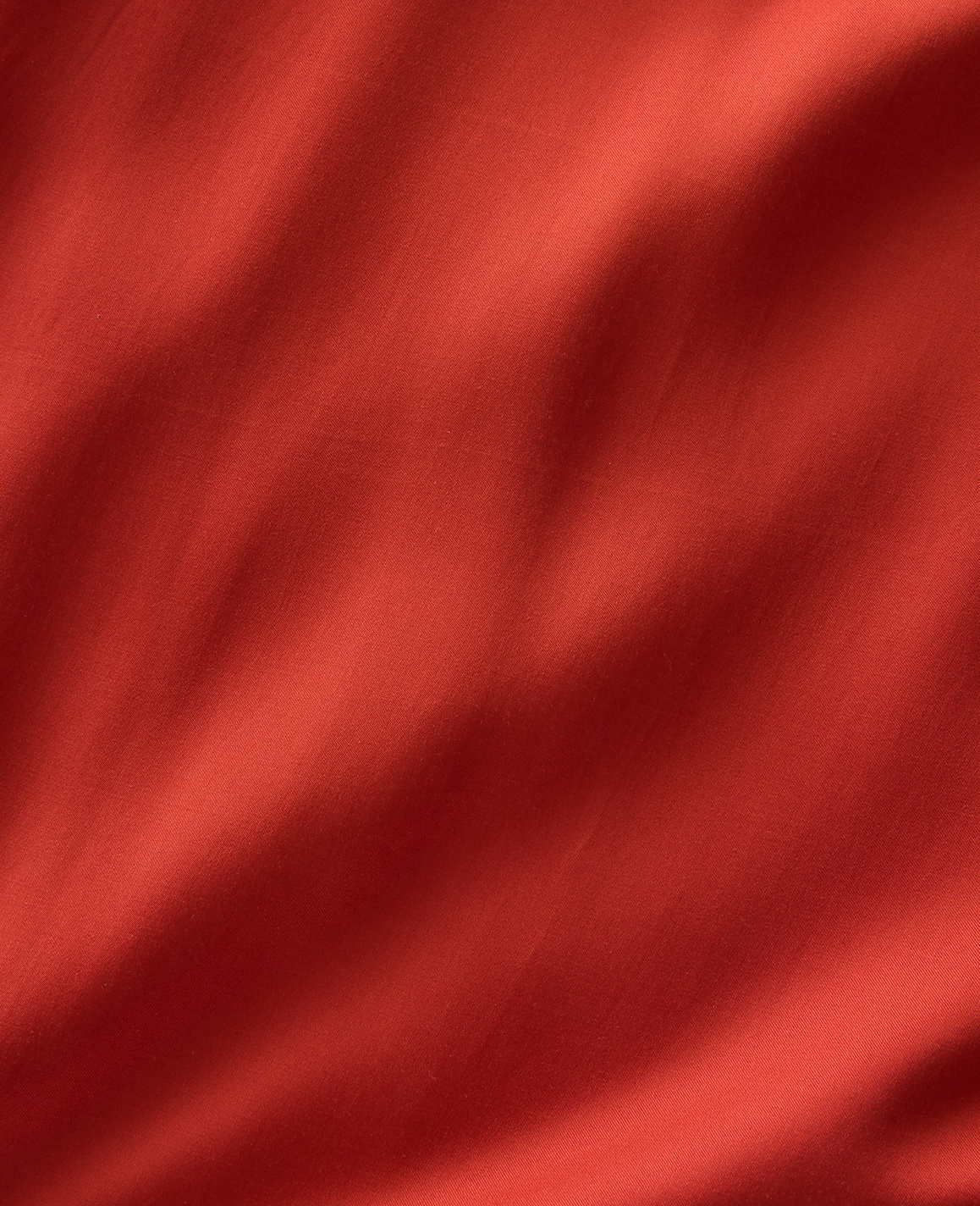 A close-up of rippling red fabric fills the frame, with soft shadows creating depth and texture.