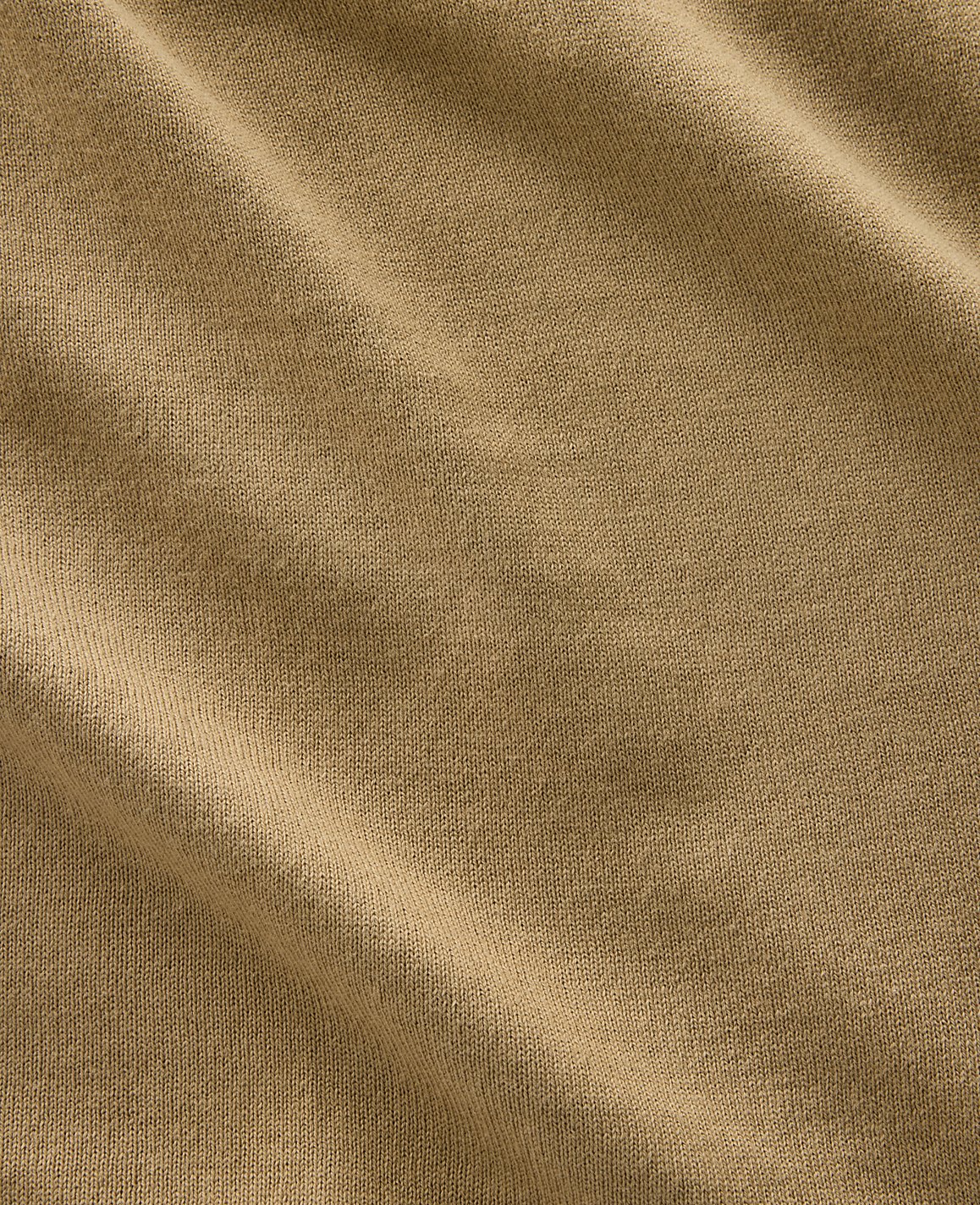 A close-up view of a tan fabric with soft folds and a textured weave fills the frame.