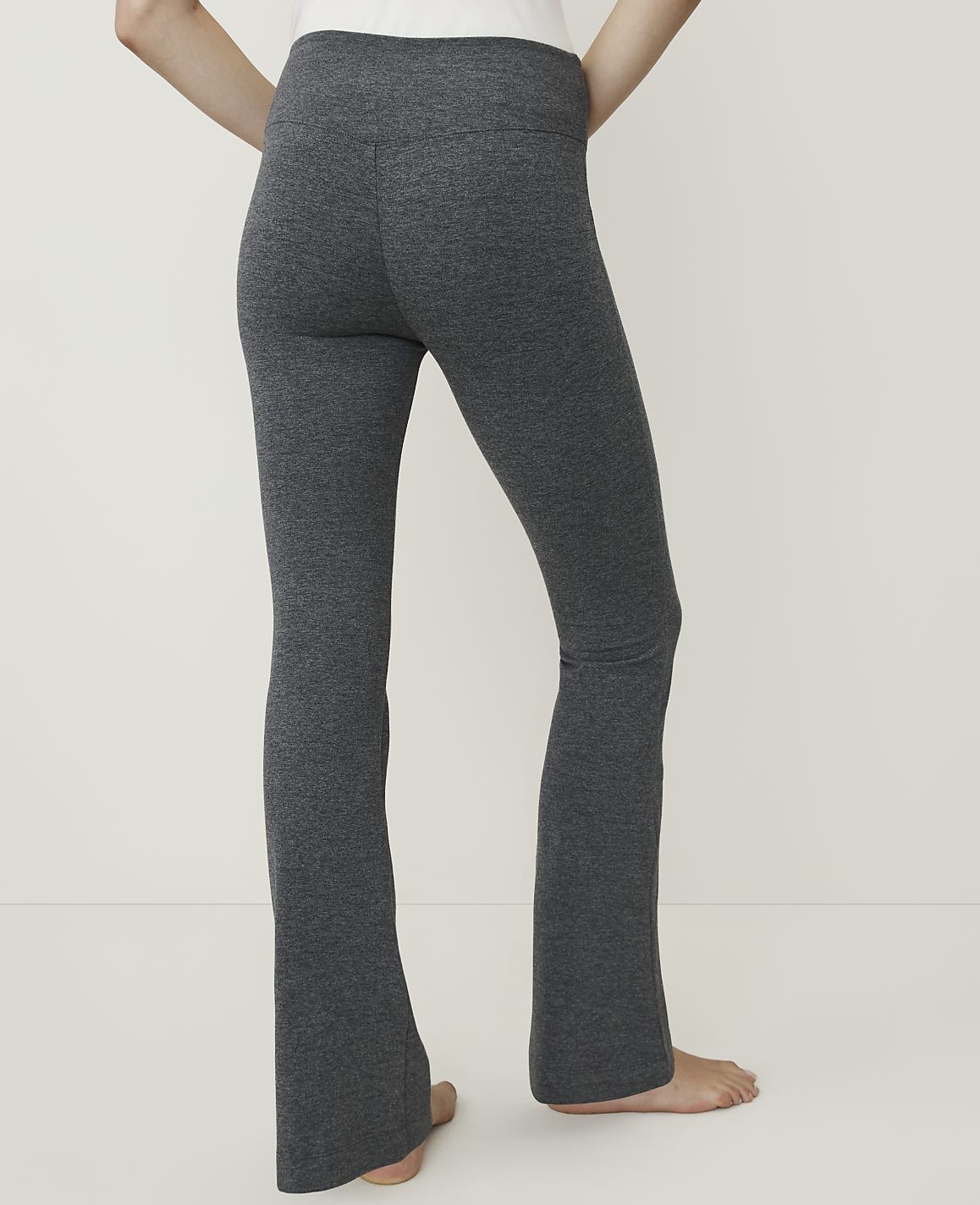 A person's legs in dark gray flared leggings are shown against a plain white background.