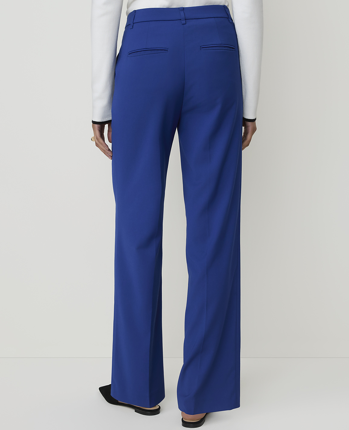 A person wearing bright blue wide-leg pants and black shoes stands against a plain white background.