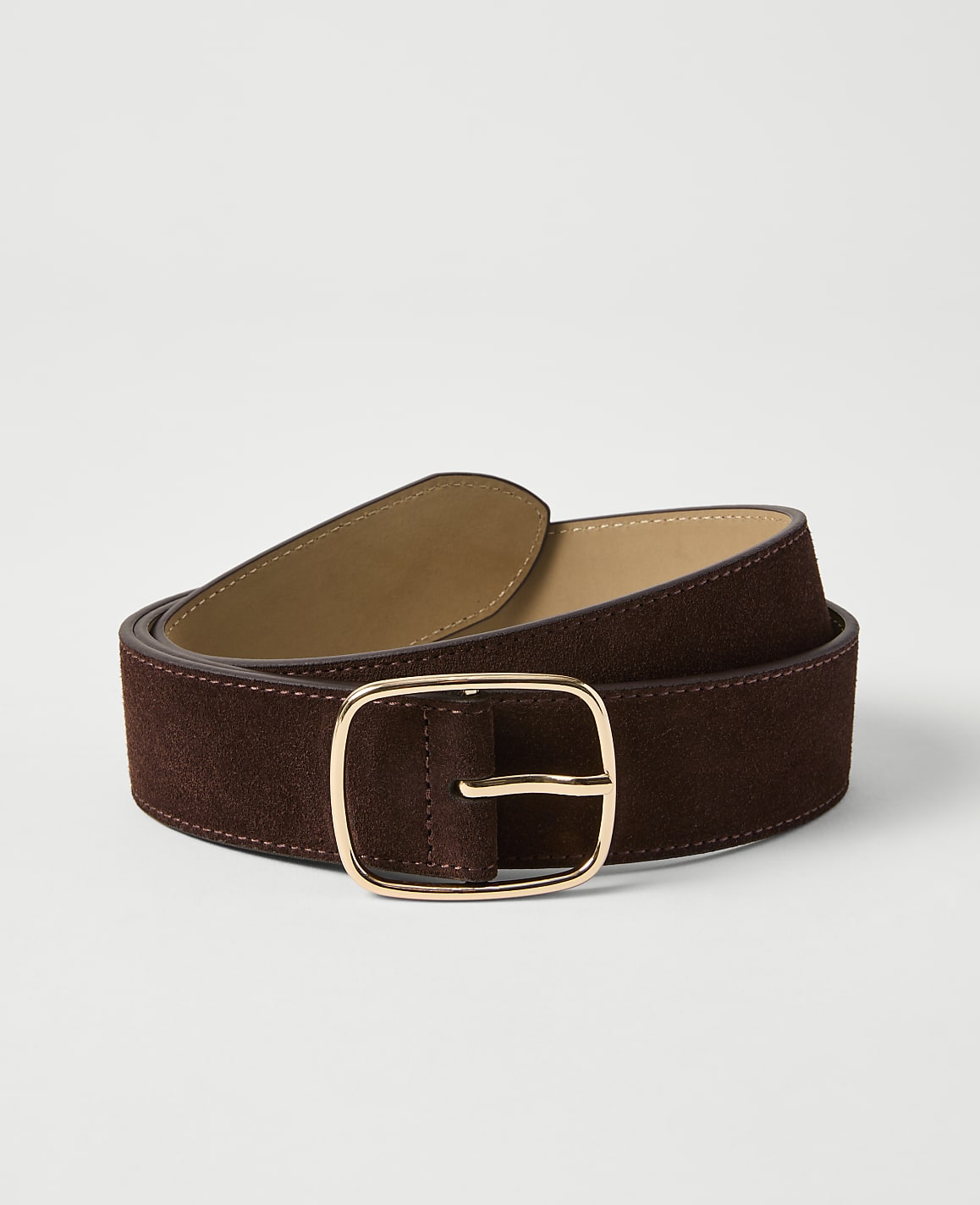 A dark brown suede belt with a gold buckle lies on a plain white background.
