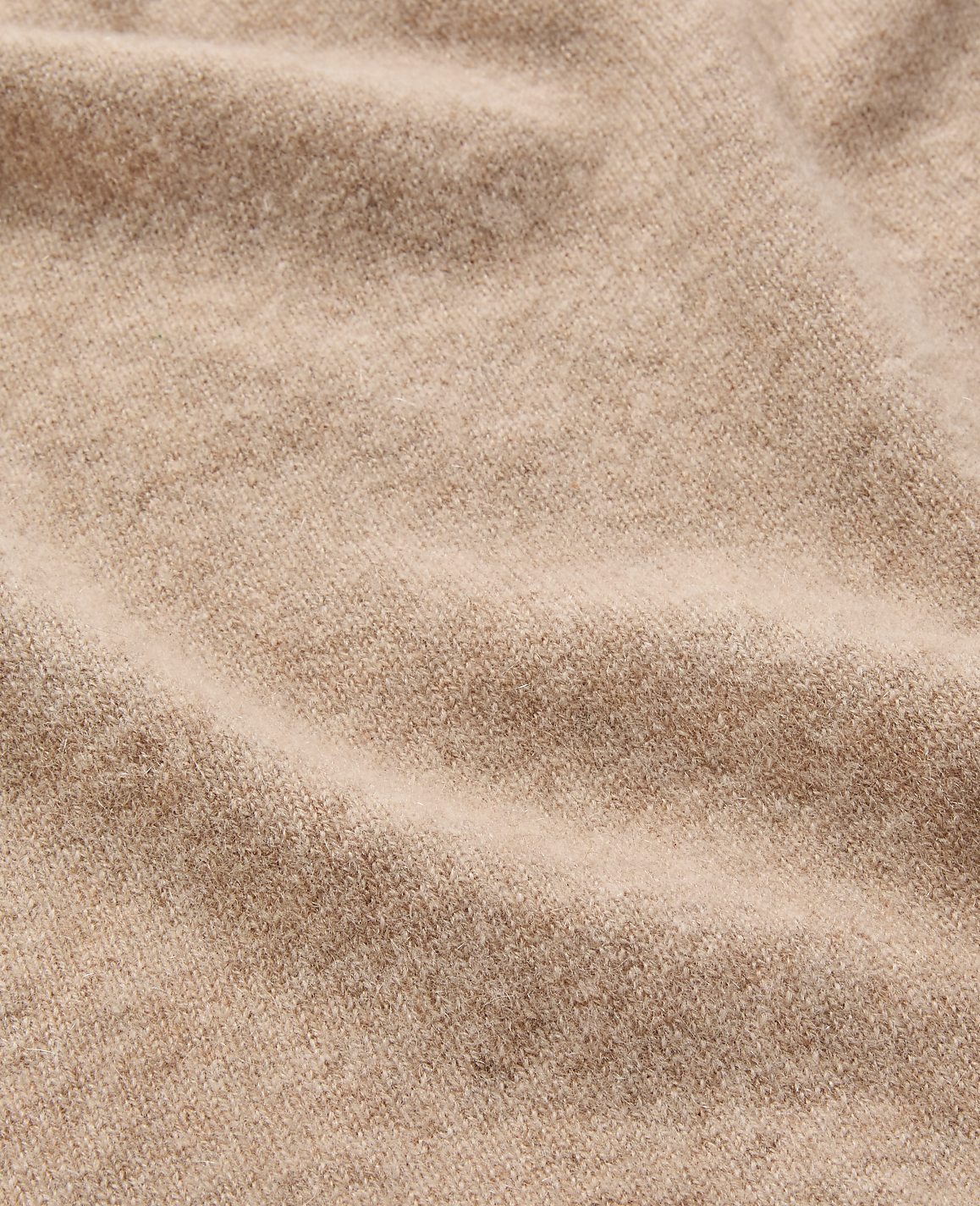 A close-up view of soft, beige fabric with gentle folds fills the frame, creating a textured and warm background.