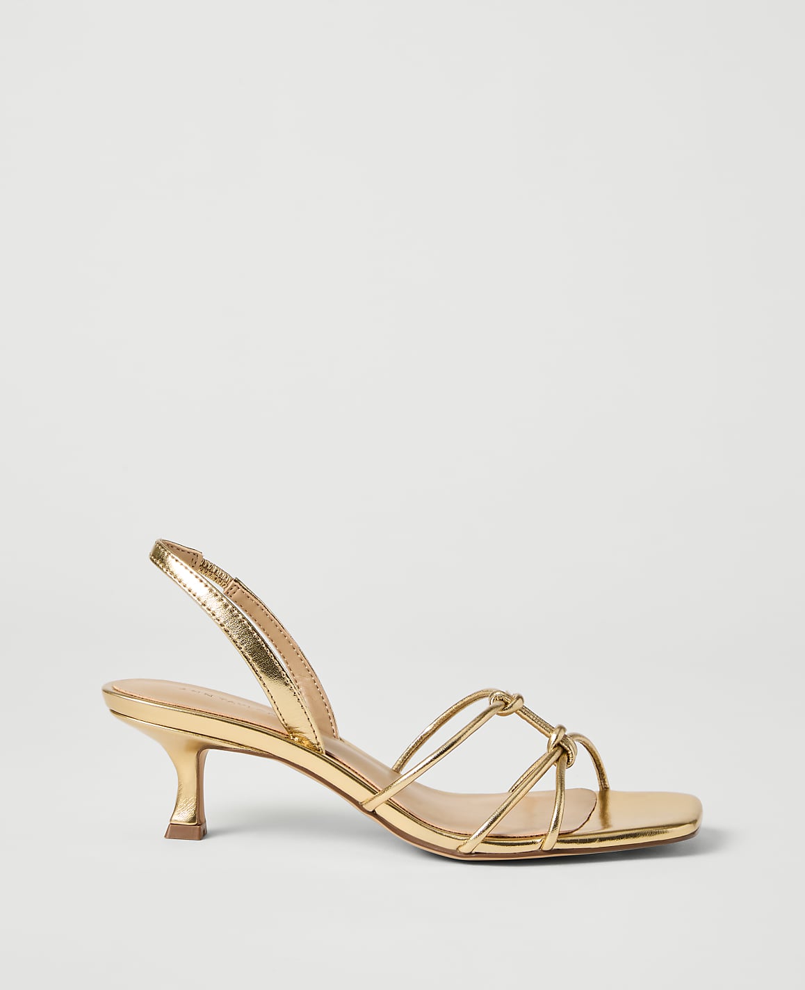 A metallic gold slingback sandal with thin straps is presented against a plain white background.