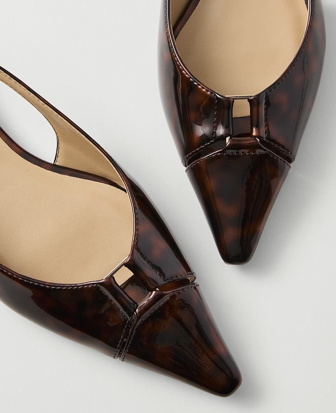 Two pointed-toe slingback heels with a tortoiseshell pattern rest on a plain white background.