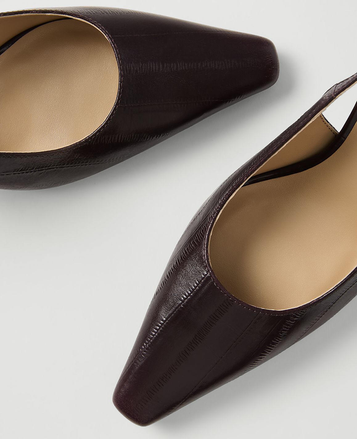 Two dark, textured slingback heels with square toes are arranged on a plain white background.