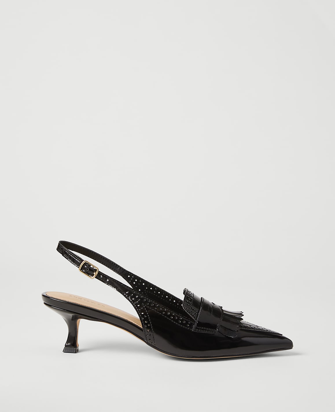 A black patent leather slingback shoe with a tassel detail sits on a plain white background.