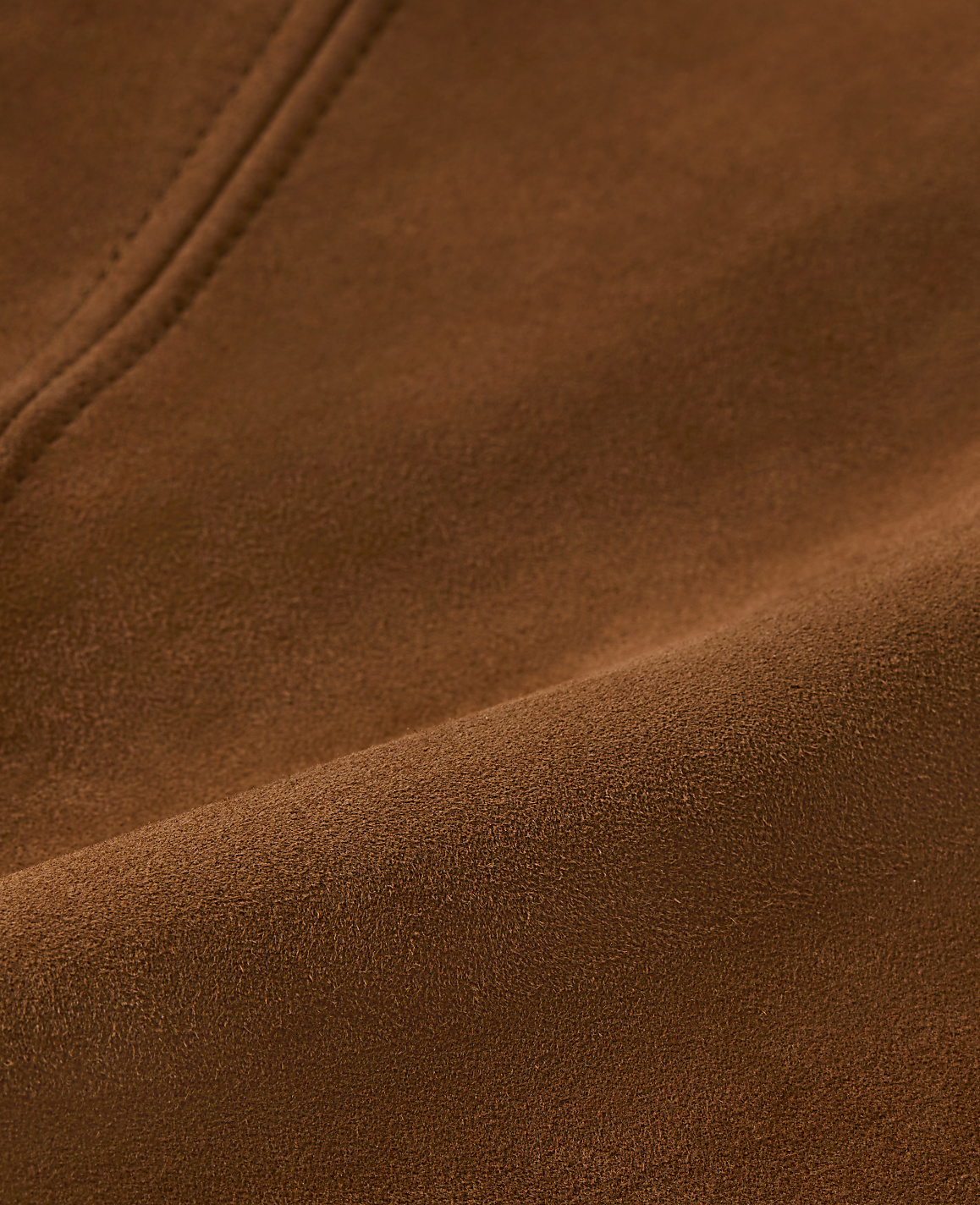 A person wears a brown suede skirt with a black belt featuring a gold buckle, against a plain white background.