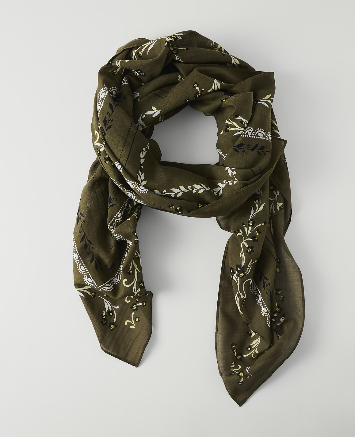 A draped olive green scarf with a white floral pattern lies on a plain white background.