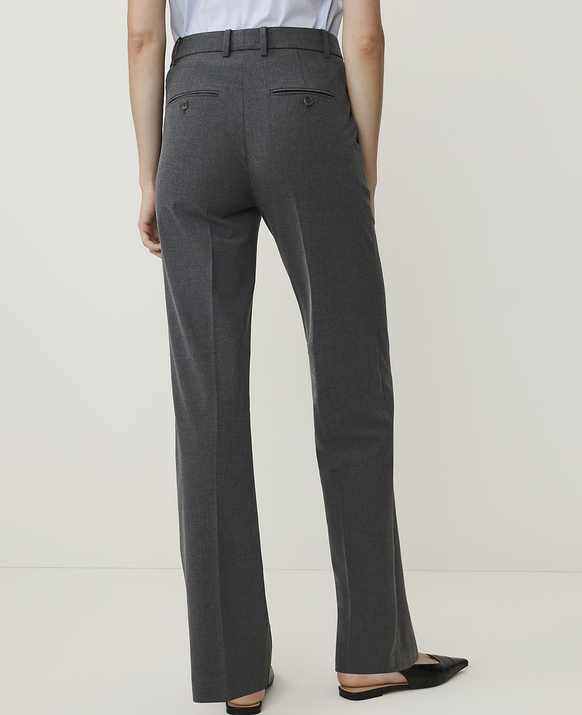 A person wearing dark gray dress pants stands against a plain white background.