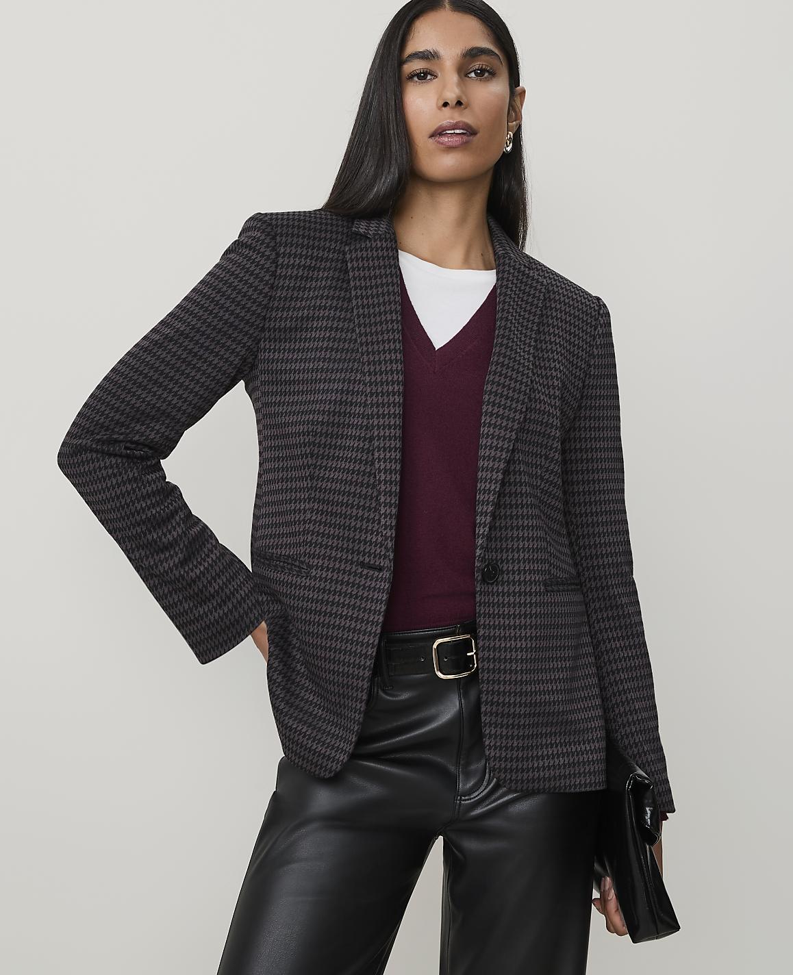 A woman in a patterned blazer and leather pants poses against a plain background.